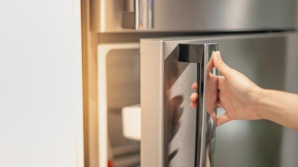 Hand opening a refrigerator door.