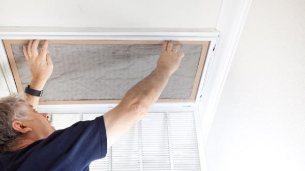 Man replacing dirty air co<em></em>nditioning filter at home.