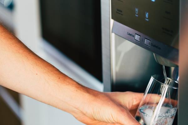 white hand getting water from fridge