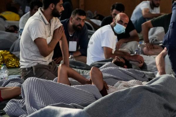 Survivors of a shipwreck rest in a warehouse at the port in Kalamata town