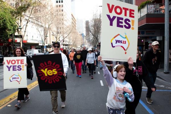 Supporters of the 'yes' campaign for the Voice to Parliament. They are carrying placards reading 'VOTE YES'