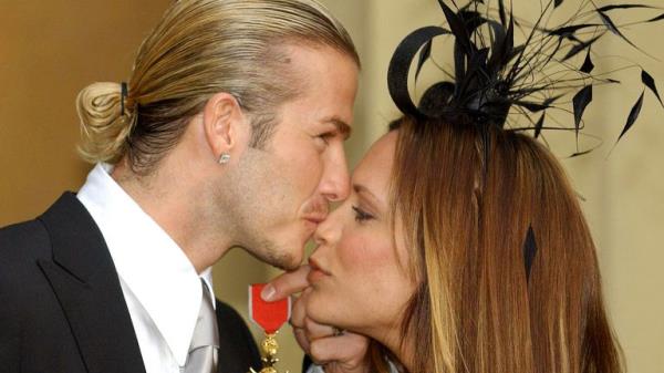 David Beckham kisses his wife, Victoria, as he holds the OBE 
Pic:AP